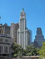 Distant ground-level view of a 60-story building; the building has setbacks on several levels and a pyramidal copper roof with several large spires.