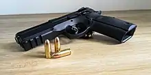 Pistolet CZ 75 SP-01 Shadow leżący na załadowanym magazynku. Obok pistoletu leżą 3 sztuki pełnopłaszczowej amunicji 9x19 mm Para.