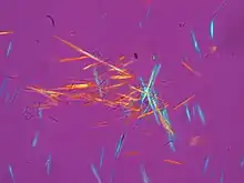 numerous multi-colored needle-shaped crystals against a purple background