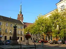 Widok na wieżę i staromiejskie kamienice. Fotografia historyczna wykonana przed wycięciem drzew na Placu Kazimierza.