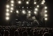 Koncert Einstürzende Neubauten podczas festiwalu Inne Brzmienia w Lublinie w 2015 roku. Na zdjęciu duża scena festiwalu a na niej zespół. Pod scena tłum publiczności.